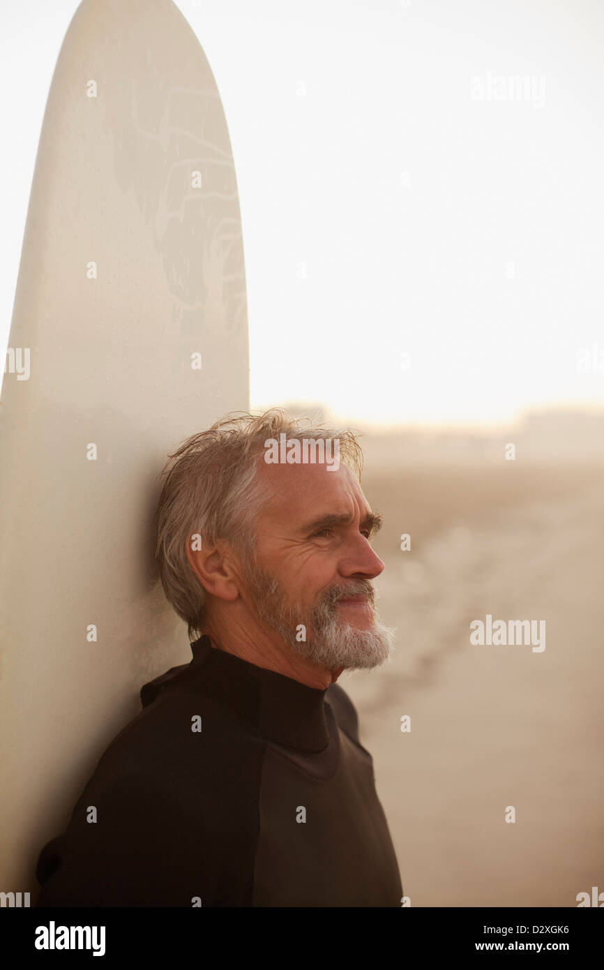 Ältere Surfer gelehnt an Bord am Strand Stockfoto