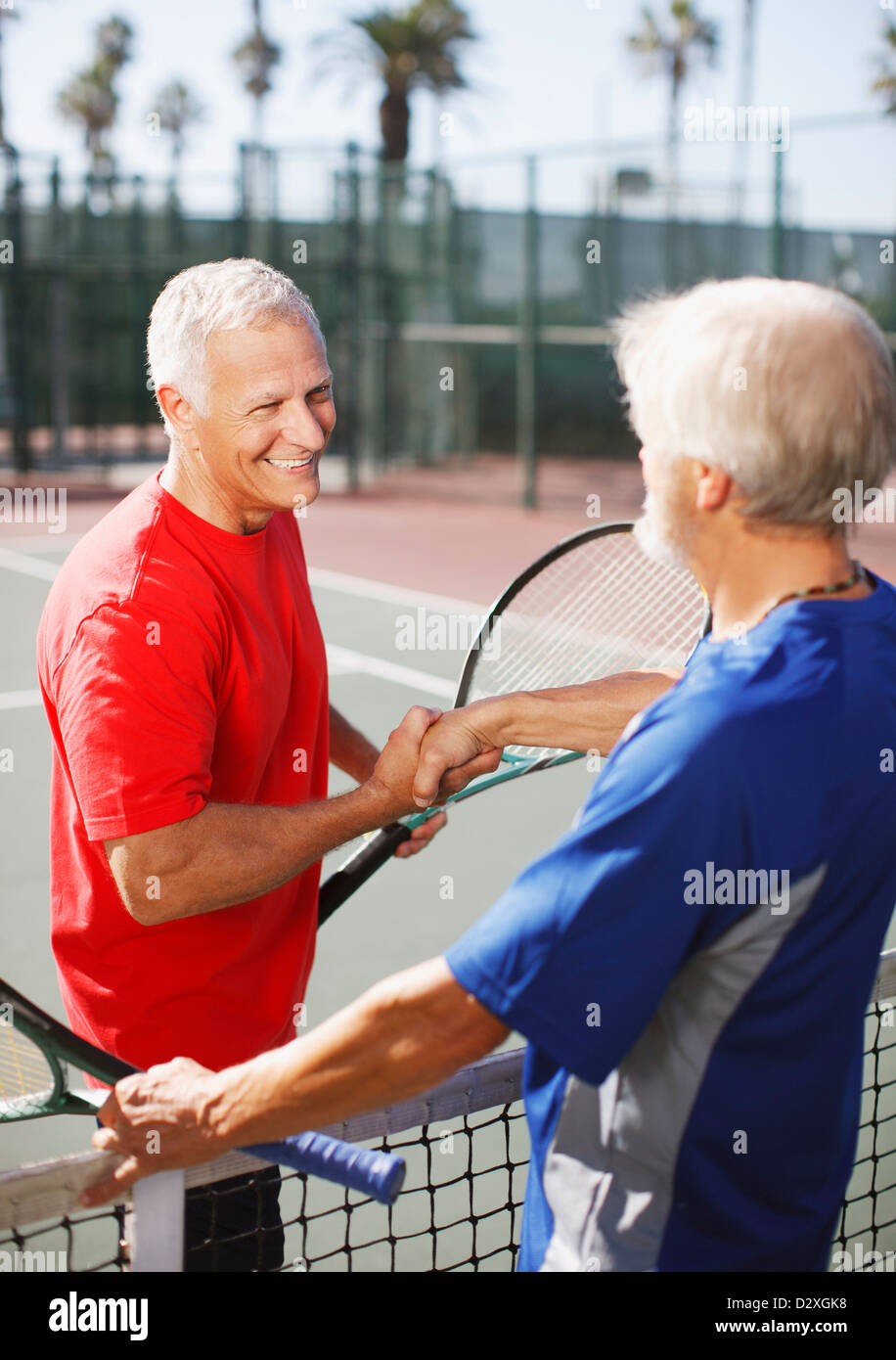 Ältere Männer Händeschütteln auf Tennisplatz Stockfoto