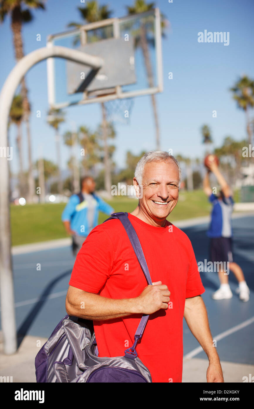 Älterer Mann mit Sporttasche auf Platz Stockfoto