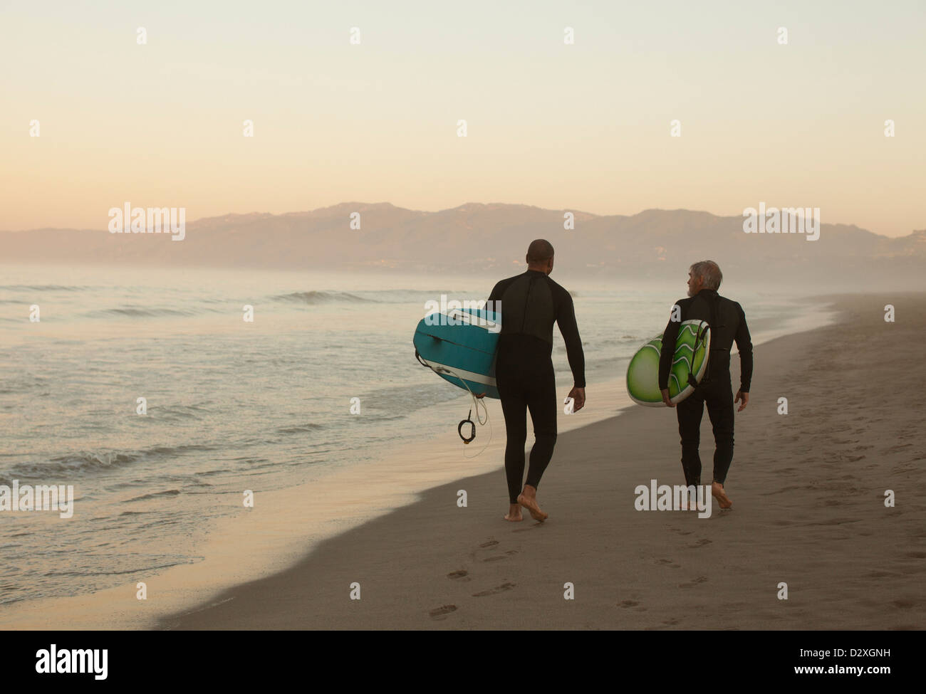 Ältere Surfer tragen Boards am Strand Stockfoto