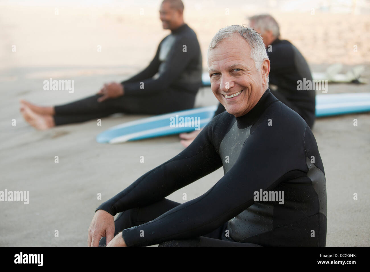 Ältere Surfer auf Boards am Strand sitzen Stockfoto