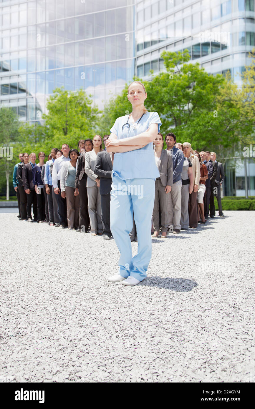 Porträt von zuversichtlich Krankenschwester mit Geschäftsleuten im Hintergrund Stockfoto