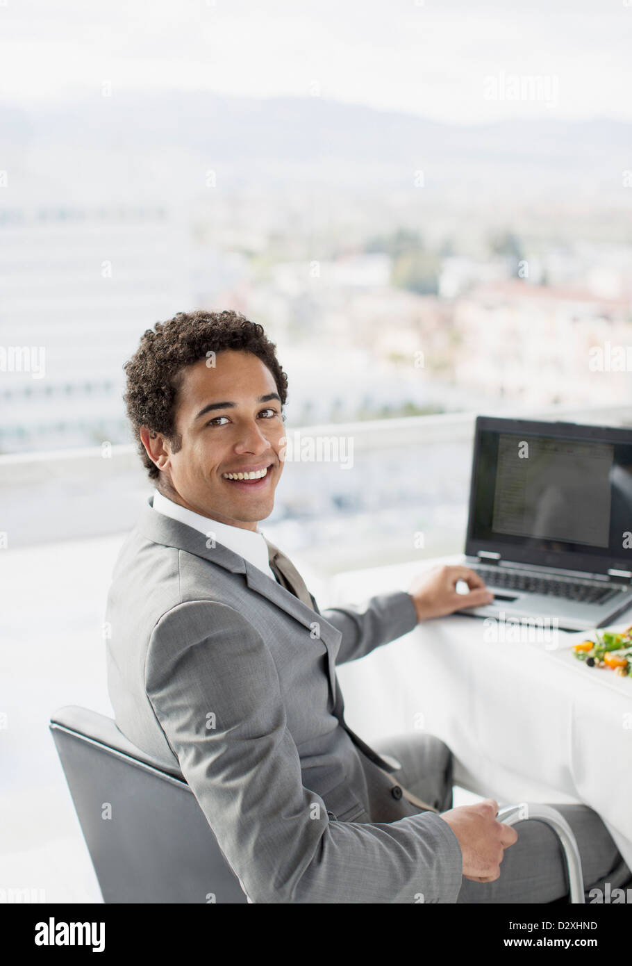 Porträt von lächelnden Geschäftsmann mit Laptop im Büro Stockfoto