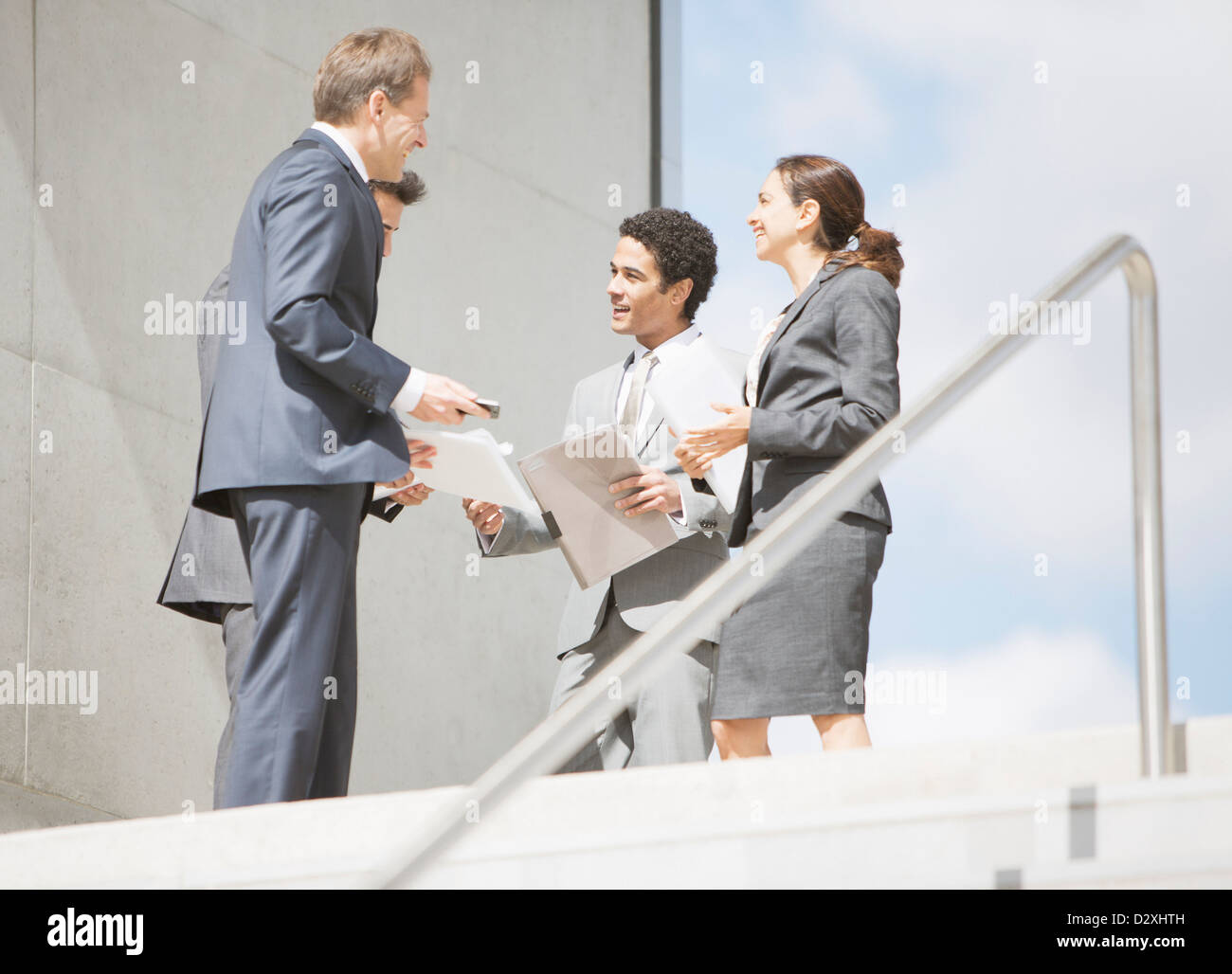 Geschäftsleute mit Papierkram treffen am Anfang der Treppe Stockfoto