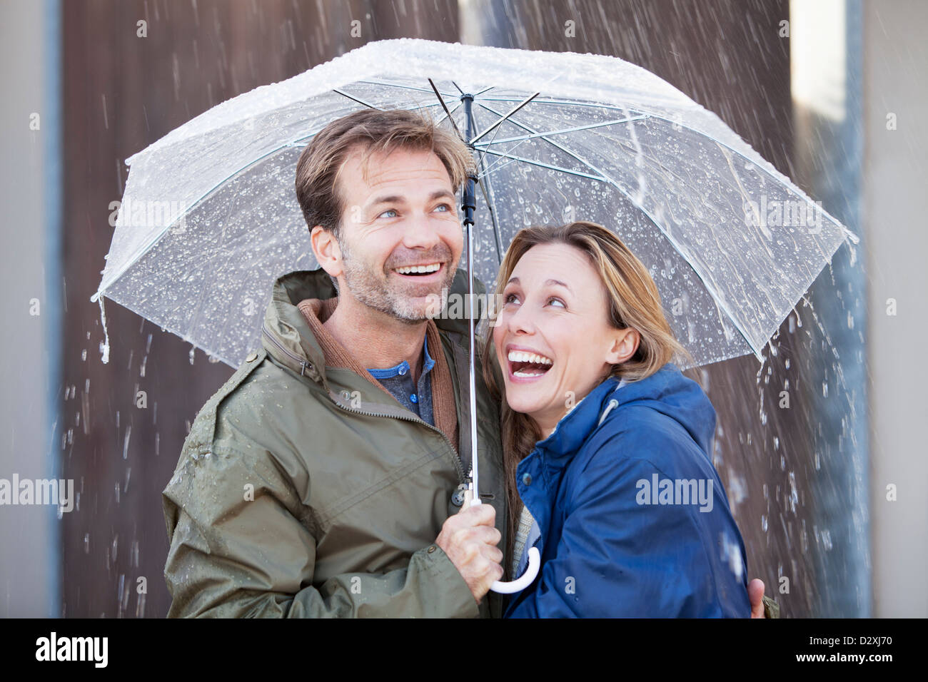 Glückliches Paar unter Dach im Regen Stockfoto