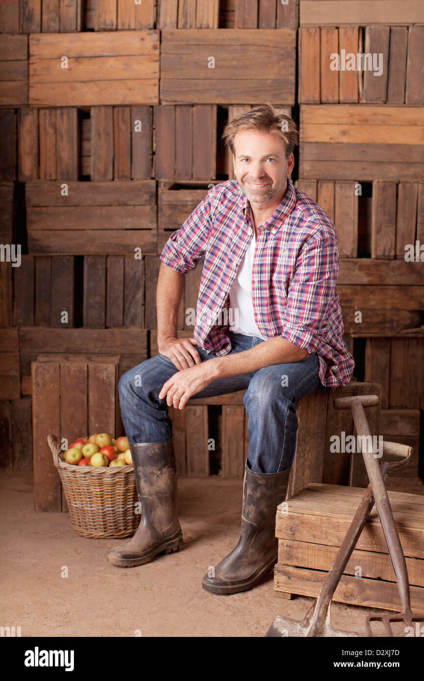 Porträt von lächelnder Mann sitzt neben Scheffel von Äpfeln Stockfoto