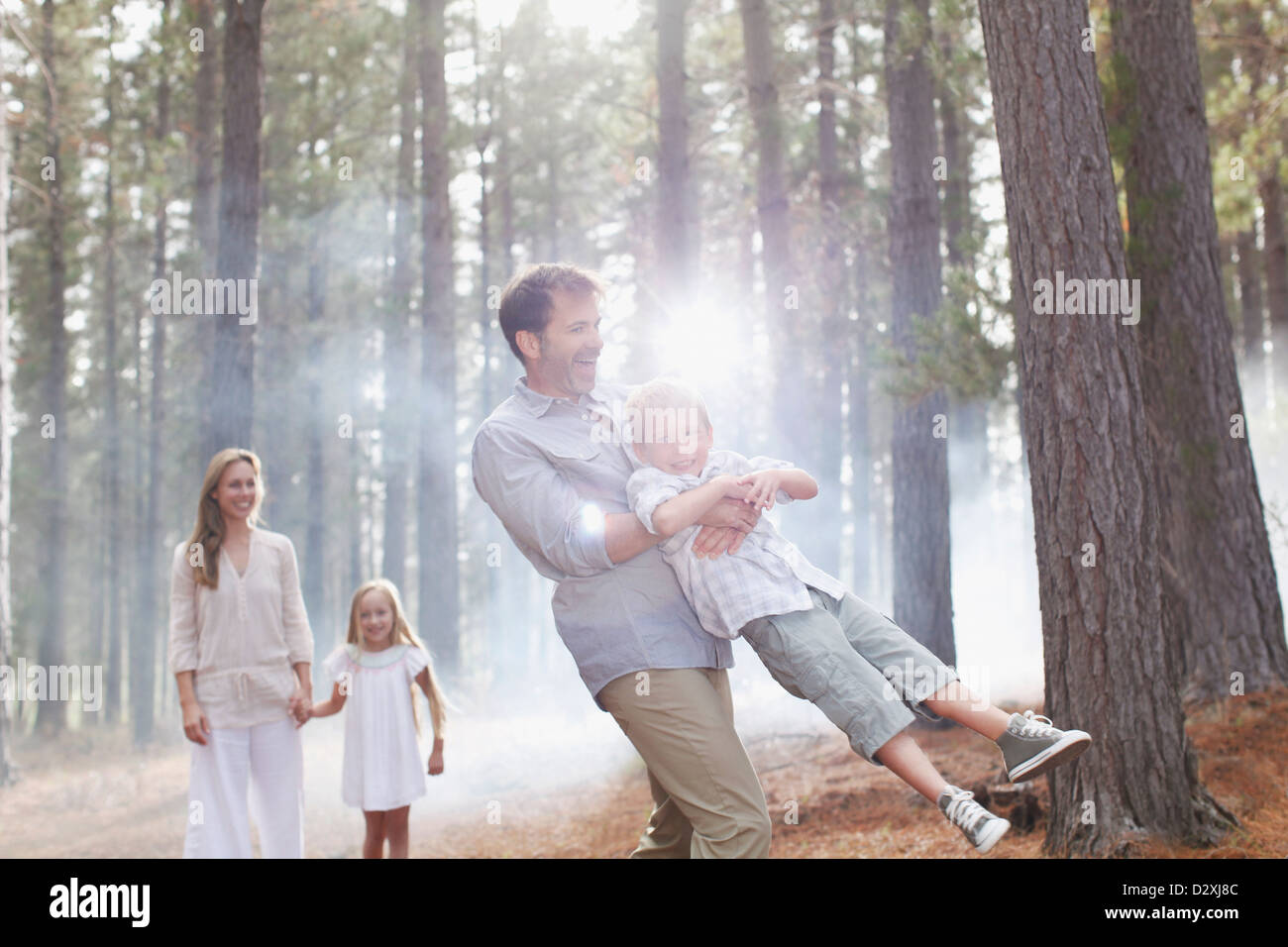 Glückliche Familie spielen in sonnigen Wäldern Stockfoto