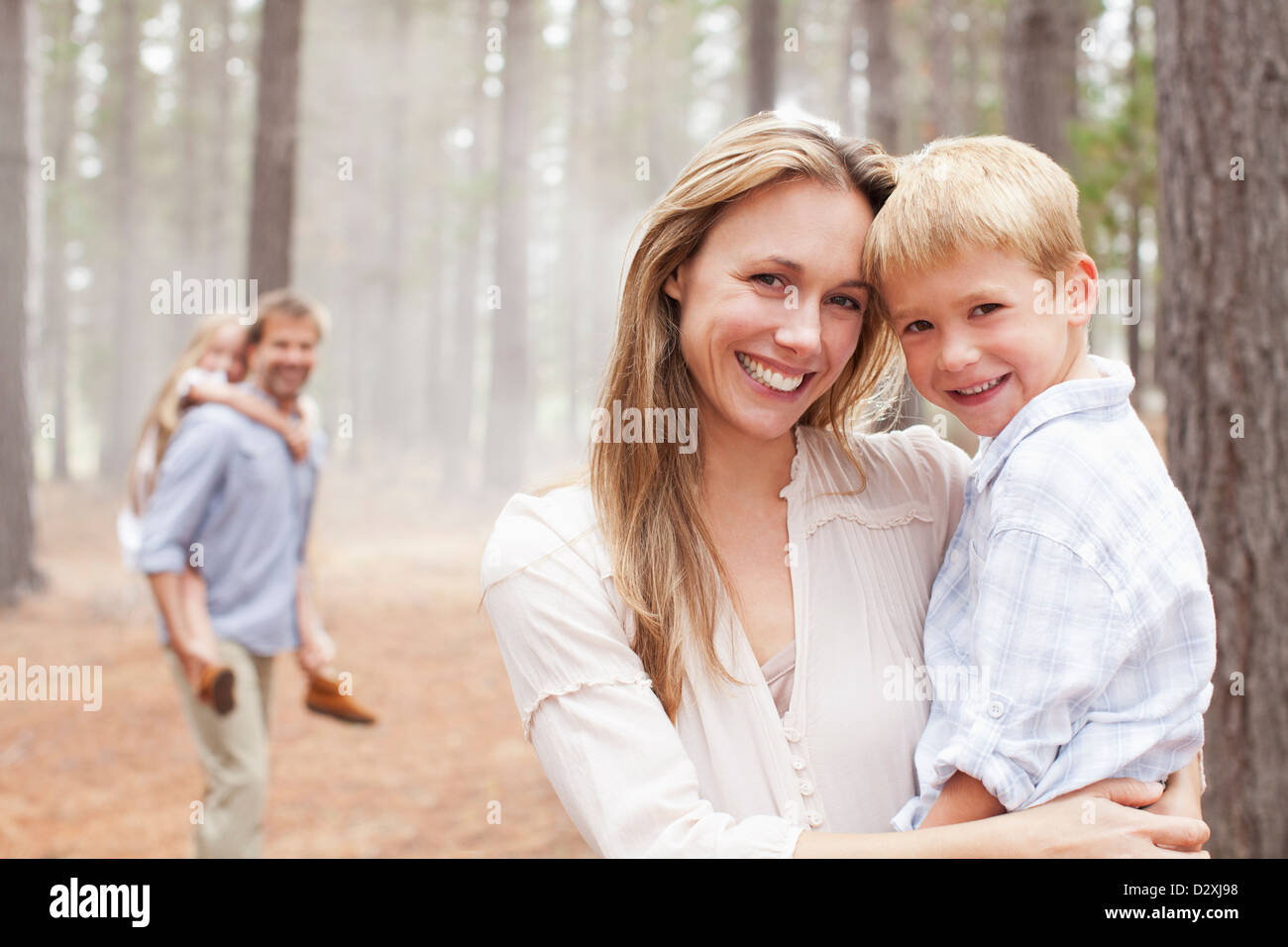 Porträt von lächelnden Mutter Holding Sohn im Wald Stockfoto