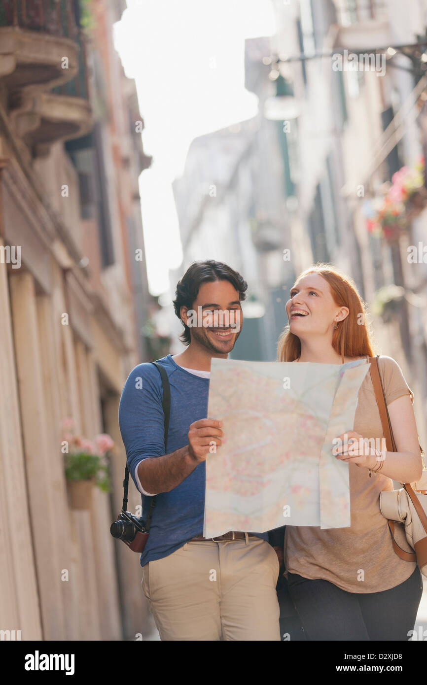 Lächelnde Paare, die mit Karte auf schmalen Straße in Venedig Stockfoto