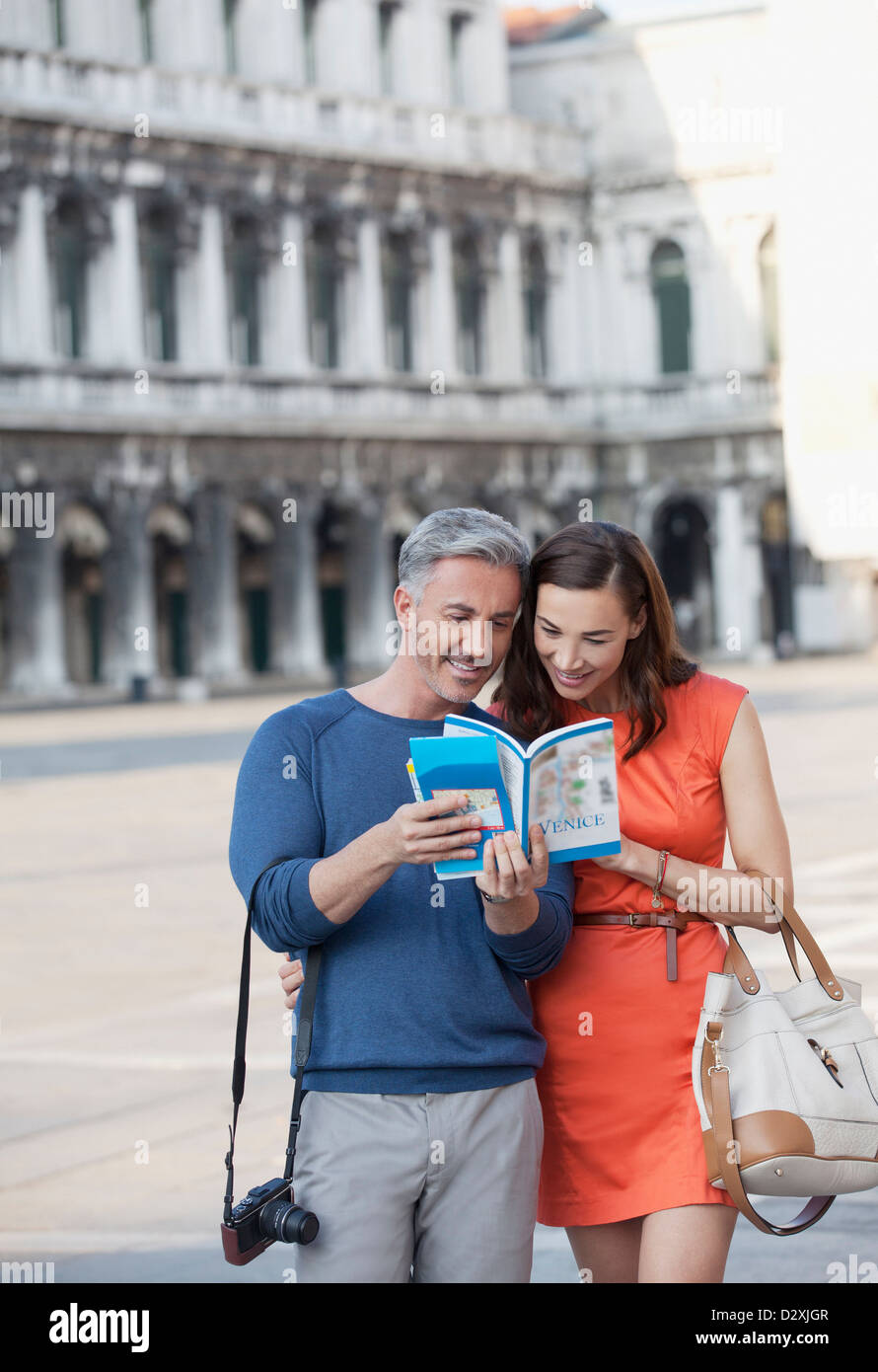 Lächelnde paar Blick auf Ratgeber in den Markusplatz in Venedig Stockfoto