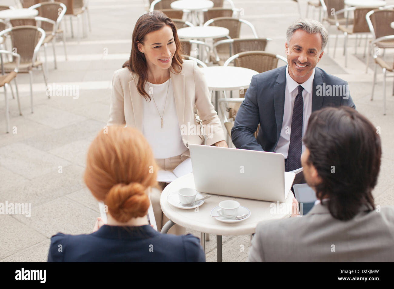 Lächelnde Geschäftsleute mit Laptop treffen am Straßencafé Stockfoto