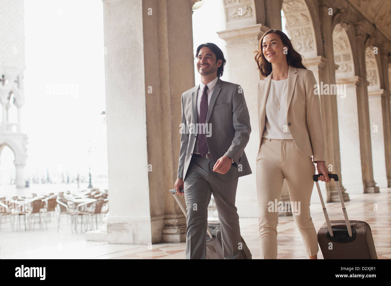 Lächelnd, Unternehmer und Unternehmerin ziehen Koffer Korridor Stockfoto