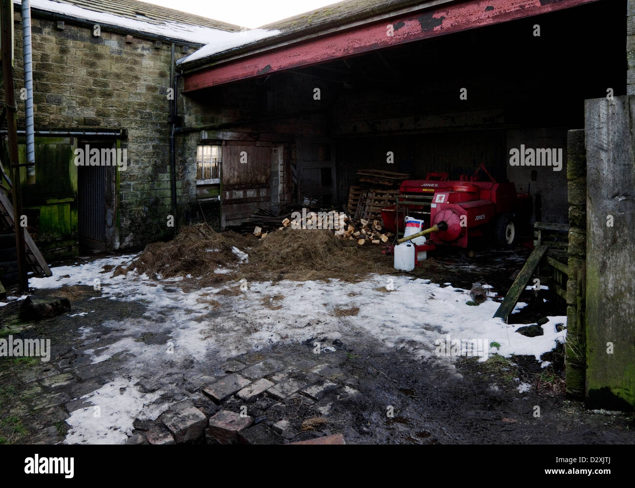 Hof im Schnee mit landwirtschaftlichen Maschinen. Stockfoto