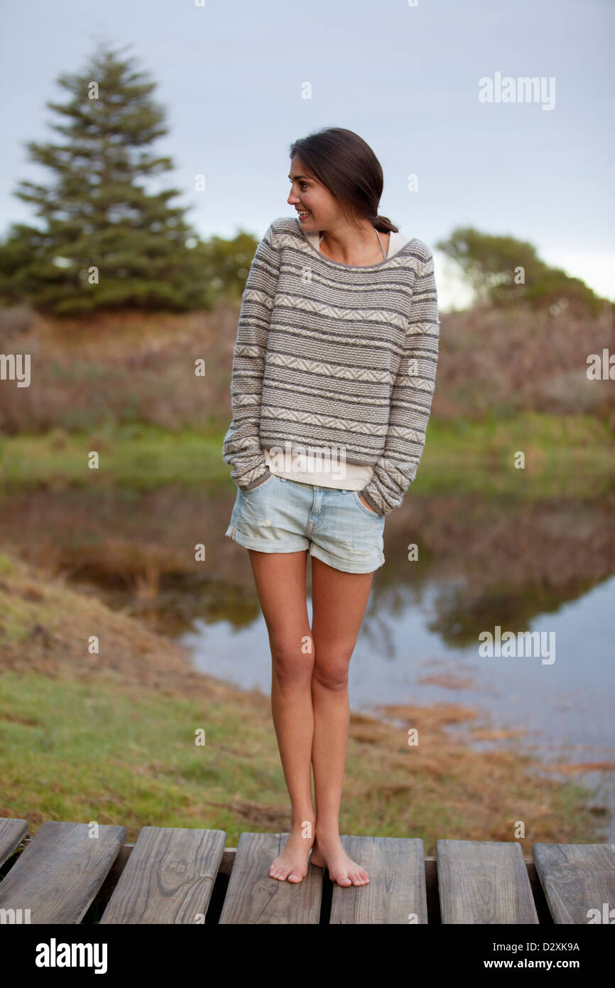 Lächelnde Frau stehend auf Dock mit Händen kurz Taschen Stockfoto