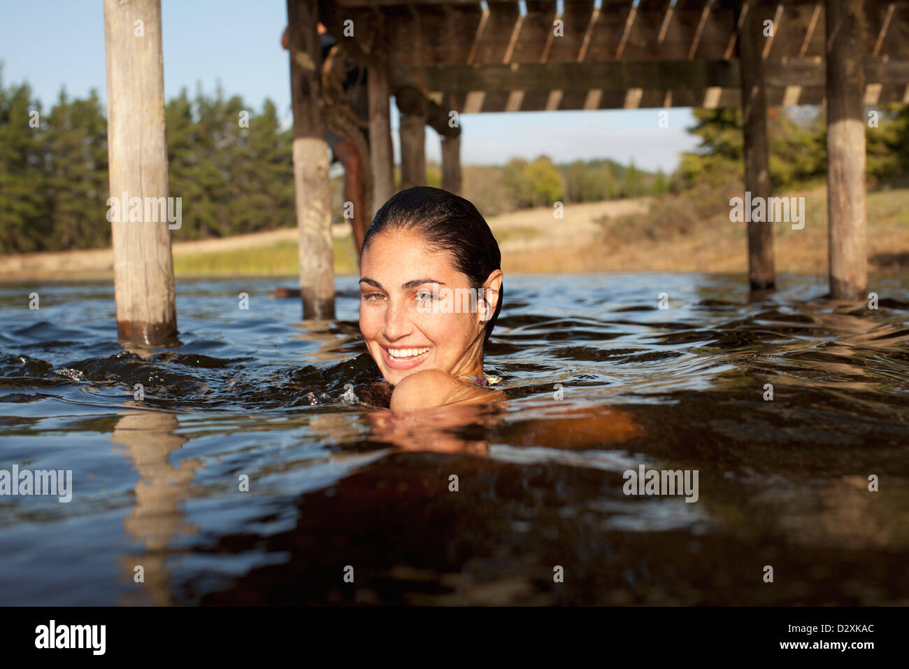 Porträt der lächelnde Frau, Schwimmen im See unter dock Stockfoto