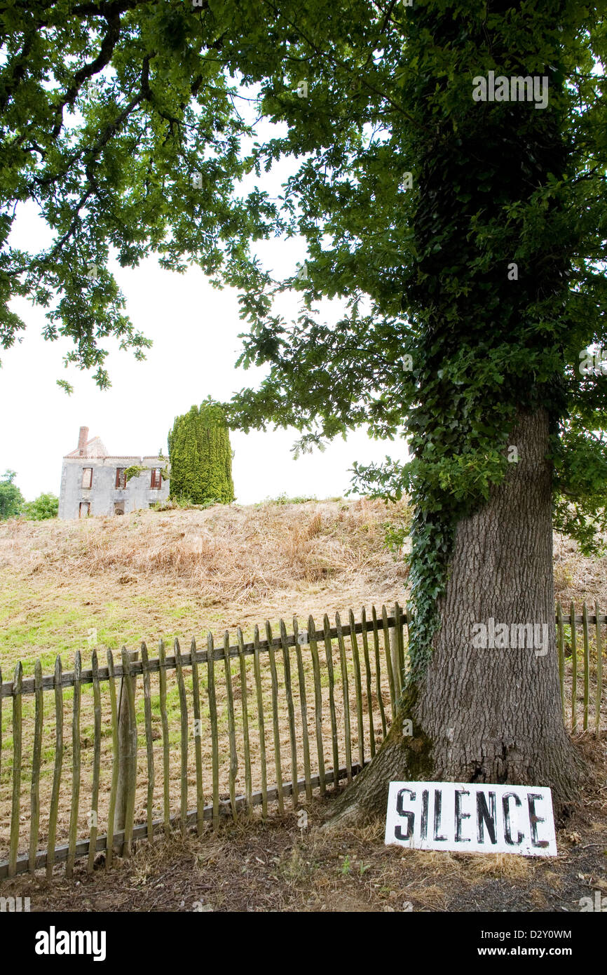 Die zerstörten französischen Dorf Oradour-Sur-Glane. Eingang hat ein Schild fordert Stille ruht gegen eine Eiche. Stockfoto