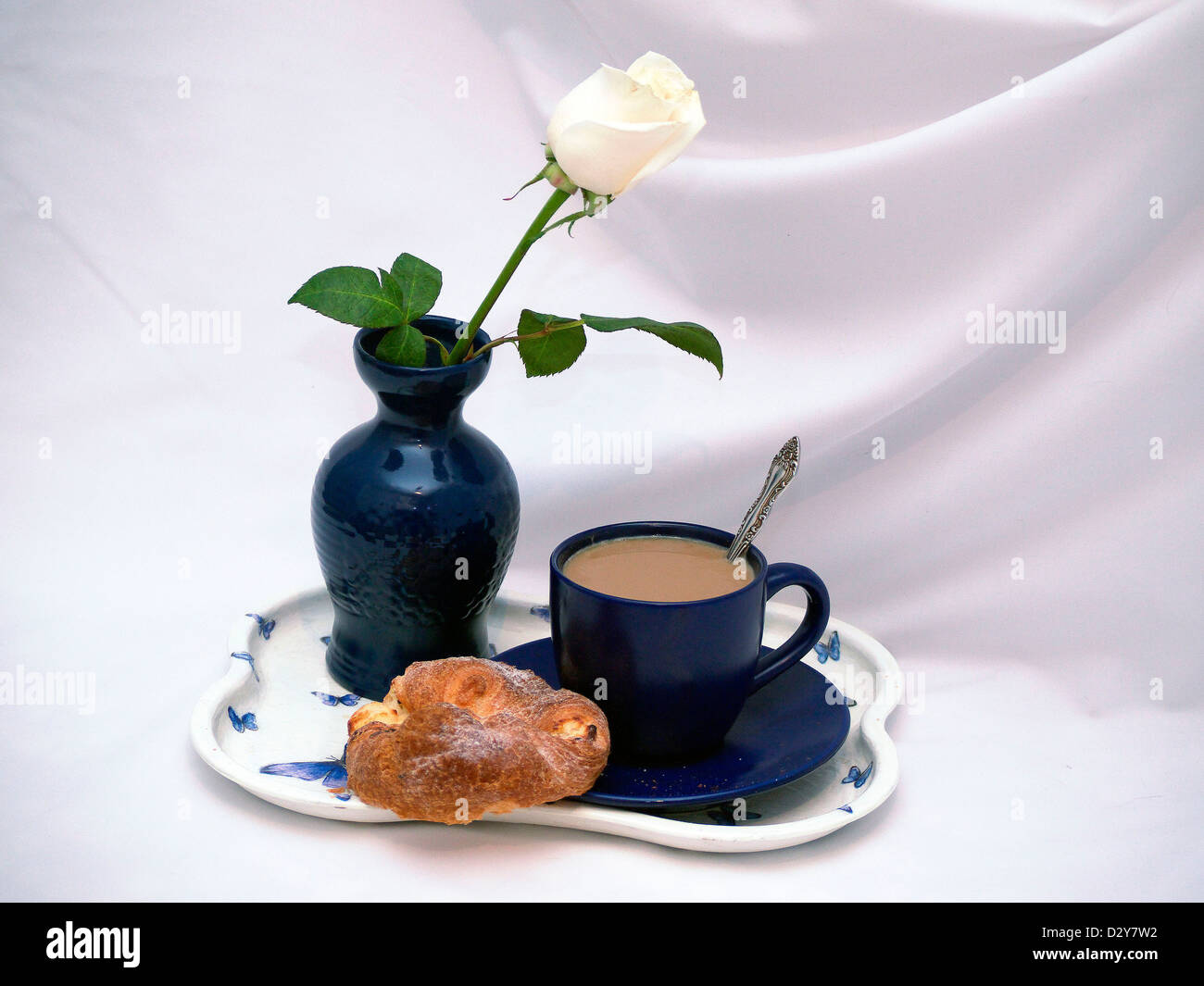 Wite Rose in blauer Vase und eine Tasse Kaffee mit Kuchen Stockfoto