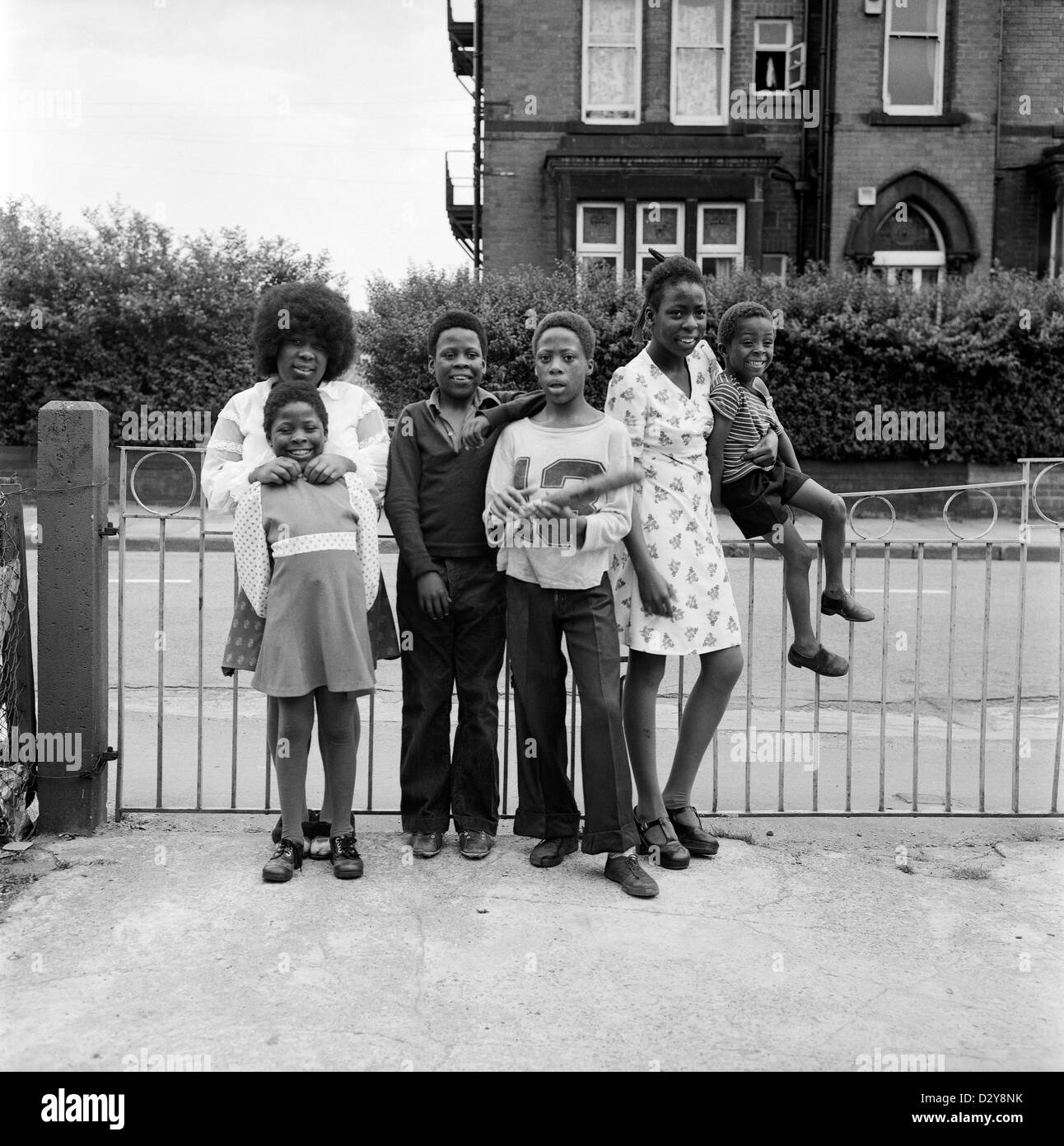 Eine Familie britischer afro-karibischer Geschwister (Familie Roper), die im Jahr 1970er in Leeds West Yorkshire England, England, lächelnd Kinder pochen. Ihre Mutter ist mit dem Baby der Familie in D2YA0M 1974 KATHY DEWITT abgebildet Stockfoto