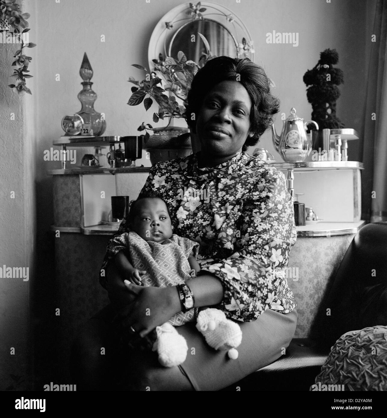 Porträt einer wunderschönen, stolzen afro-karibischen britischen Mutter (Familie Roper), die ihr kleines Baby in ihrem Wohnzimmer in Leeds West Yorkshire England Großbritannien 1970er 1974 KATHY DEWITT hielt Stockfoto
