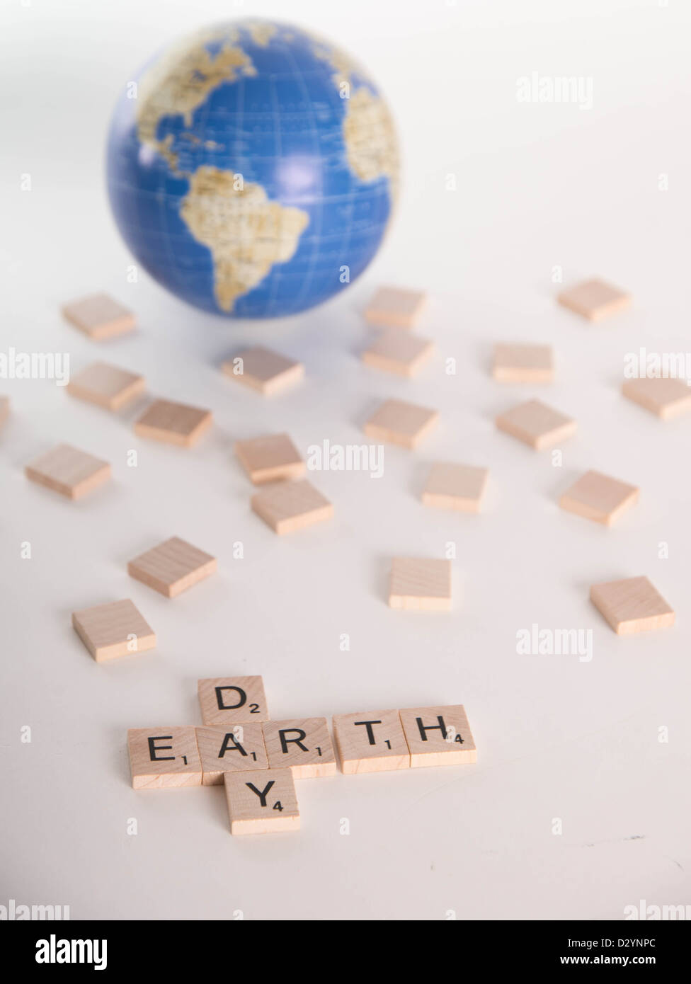 Konzept: "Earth Day" ausgeschrieben in Scrabble Buchstaben mit aus Fokus Globus im Hintergrund. Isoliert auf weißem Hintergrund. Stockfoto