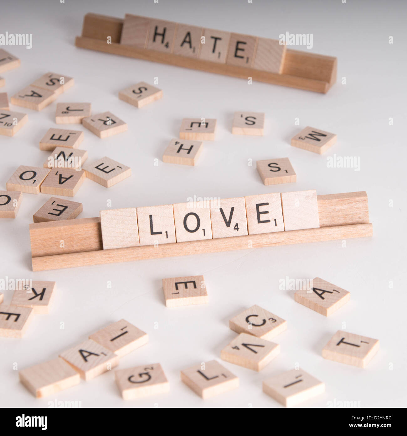 Hölzerne Scrabble Buchstaben buchstabieren "Love" und "Hassen". "Hasse" im Hintergrund unscharf. Isoliert auf weißem Hintergrund. Stockfoto