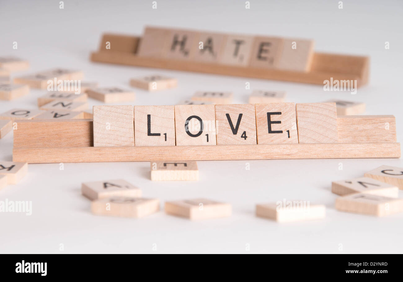 Hölzerne Scrabble Buchstaben buchstabieren "Love" und "Hassen". "Hasse" im Hintergrund unscharf. Isoliert auf weißem Hintergrund. Stockfoto