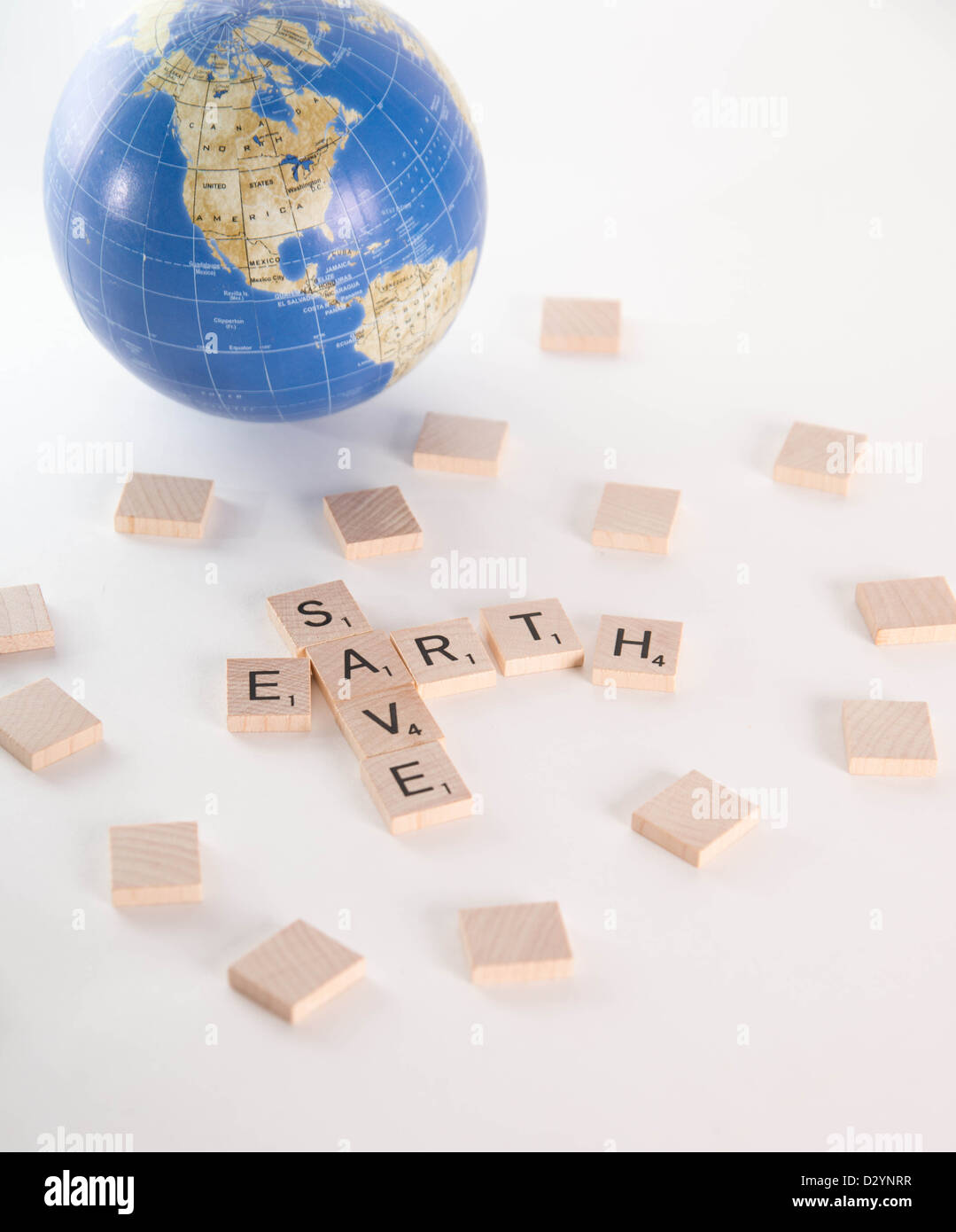 Speichern Sie Erde Konzept dargelegt in Scrabble Buchstaben mit aus Fokus Weltkugel im Hintergrund. Isoliert auf weißem Hintergrund Stockfoto