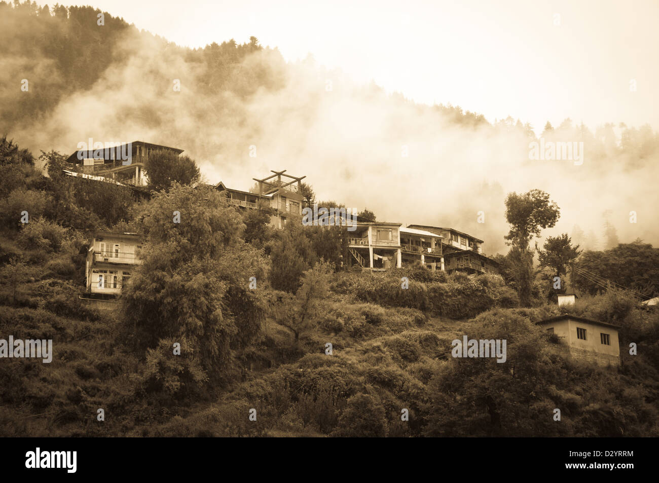 Häuser in hohe Berge bedeckt durch Nadelwald, Wolken und Regen, Nord-Indien Stockfoto