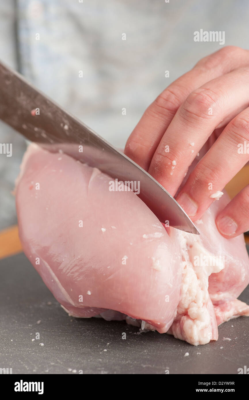 Küchenchef, Schneiden von rohem Hühnerfleisch Stockfoto