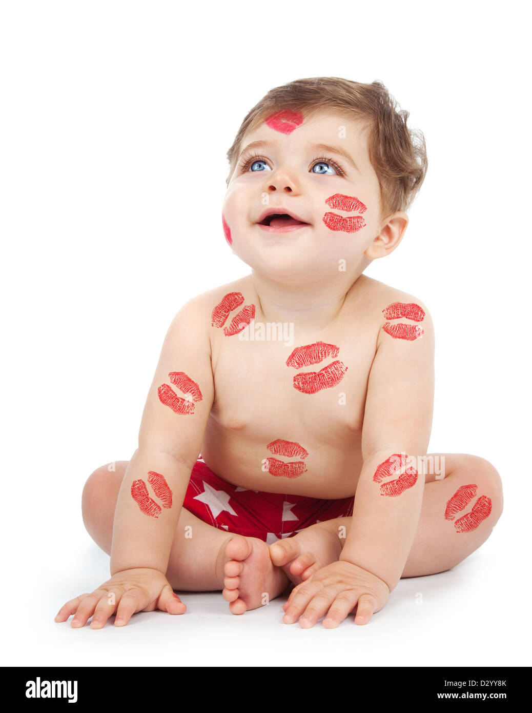 Foto von glückliches Kind bedeckt mit Druck auf den Körper, rote Küsse entzückende Baby Junge sitzt im Studio isoliert auf weißem Hintergrund, Stockfoto