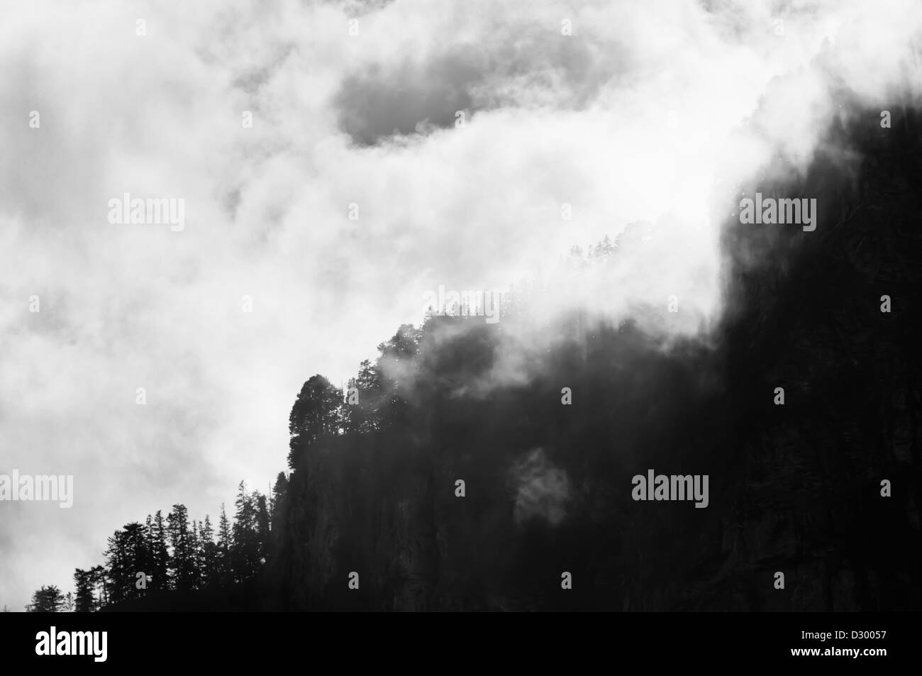 Berggipfel mit Bäumen auf dem Gipfel eingehüllt in Wolken, Himalaya Stockfoto