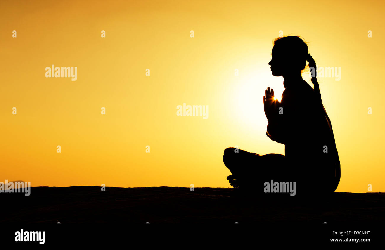 Indische Teenager-Mädchen in der indischen Landschaft bei Sonnenuntergang zu beten. Silhouette. Indien Stockfoto