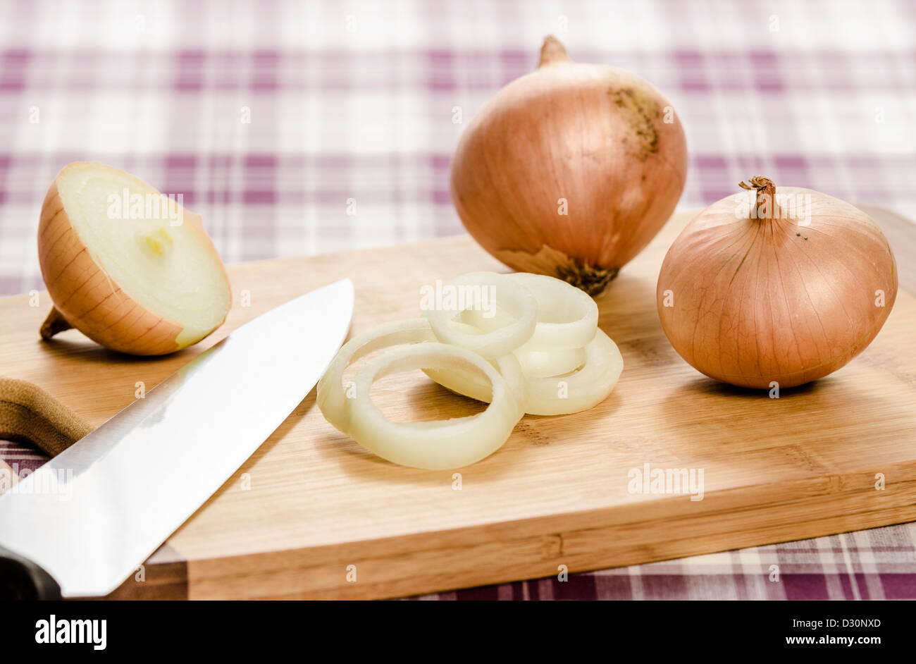 Zwiebeln und Zwiebelringe auf Schneidebrett mit Messer. Stockfoto