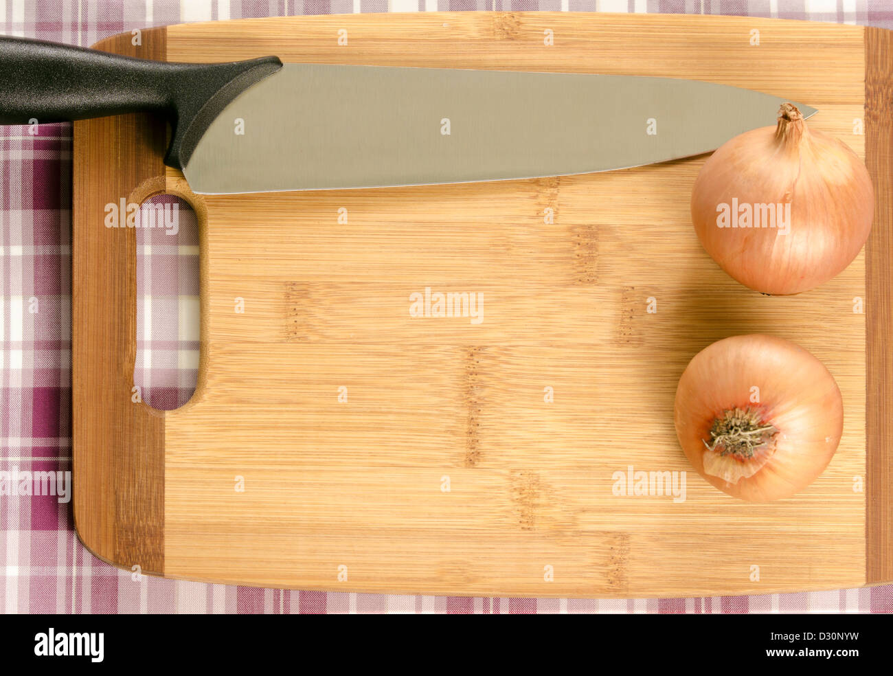 Ein Schneidebrett mit Textfreiraum. Umrahmt mit einem Messer und zwei Zwiebeln. Stockfoto