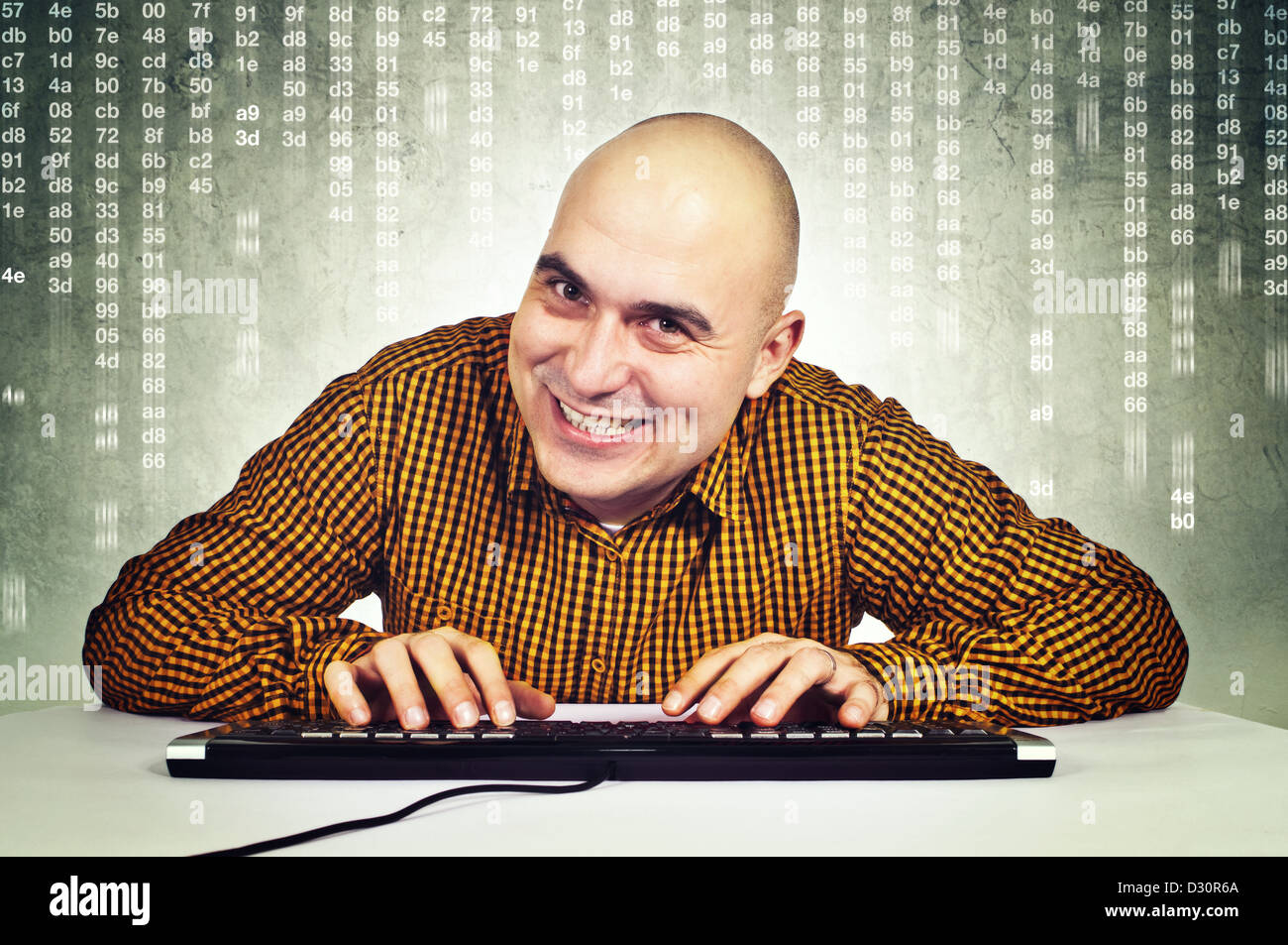 Glatze jungen Erwachsenen männlichen Computer-Hacker am Tisch mit Tastatur vor dem Monitor sitzen Stockfoto