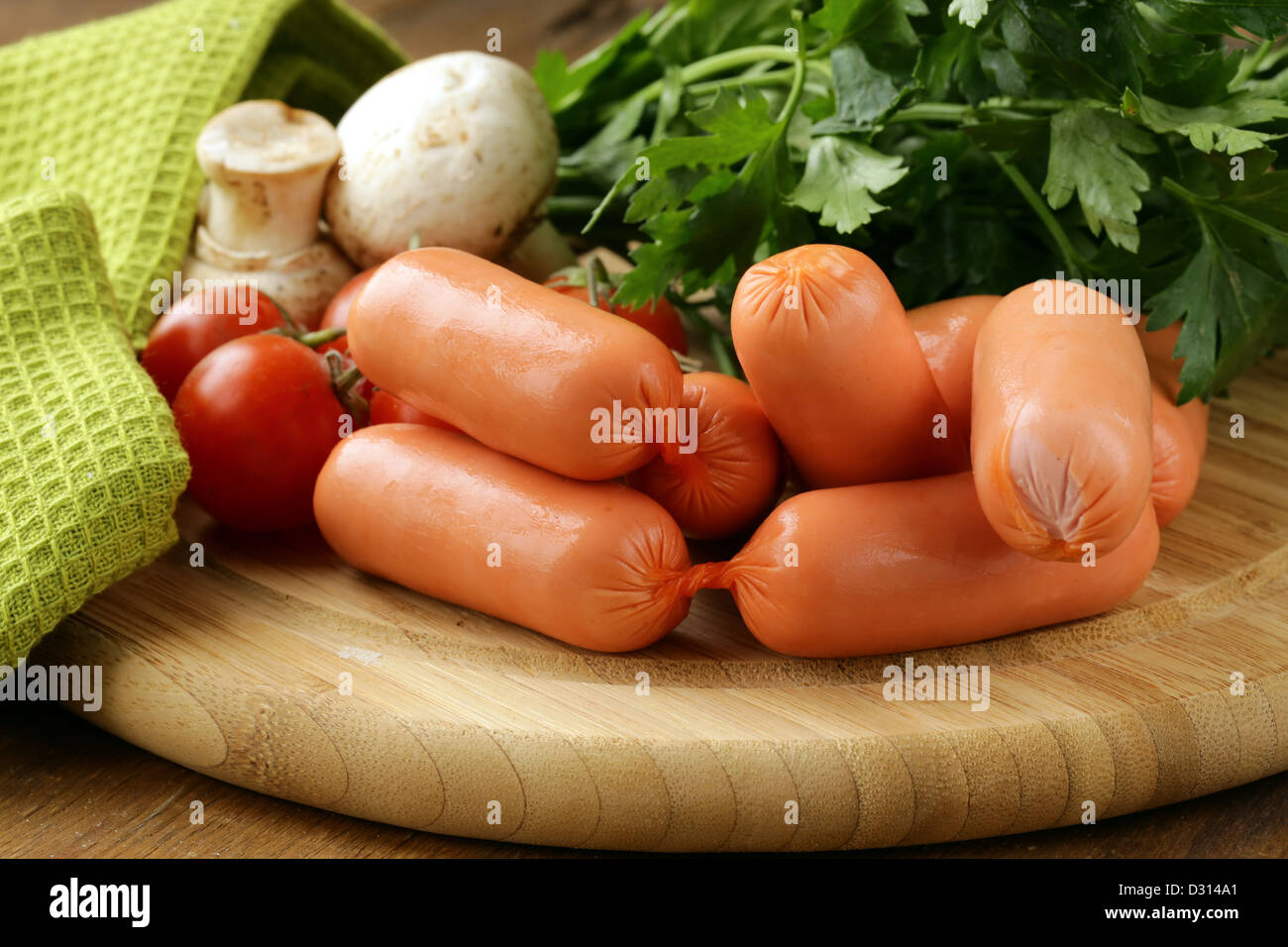 frische Würste und Petersilie auf Holzbrett Stockfoto