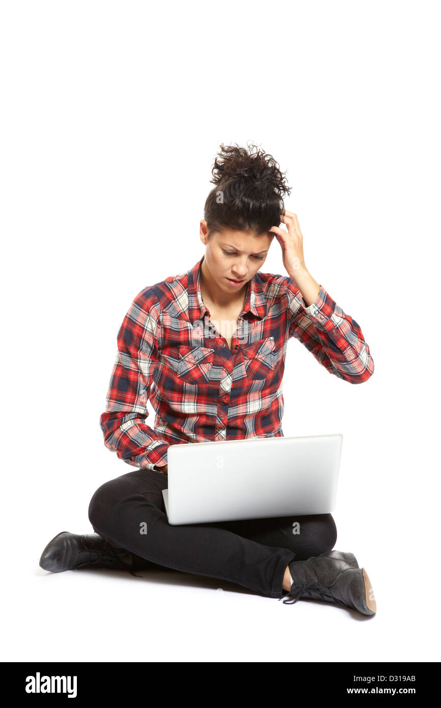 Junge Frau mit Laptop sitzen auf weißem Hintergrund schauen verwirrt Stockfoto