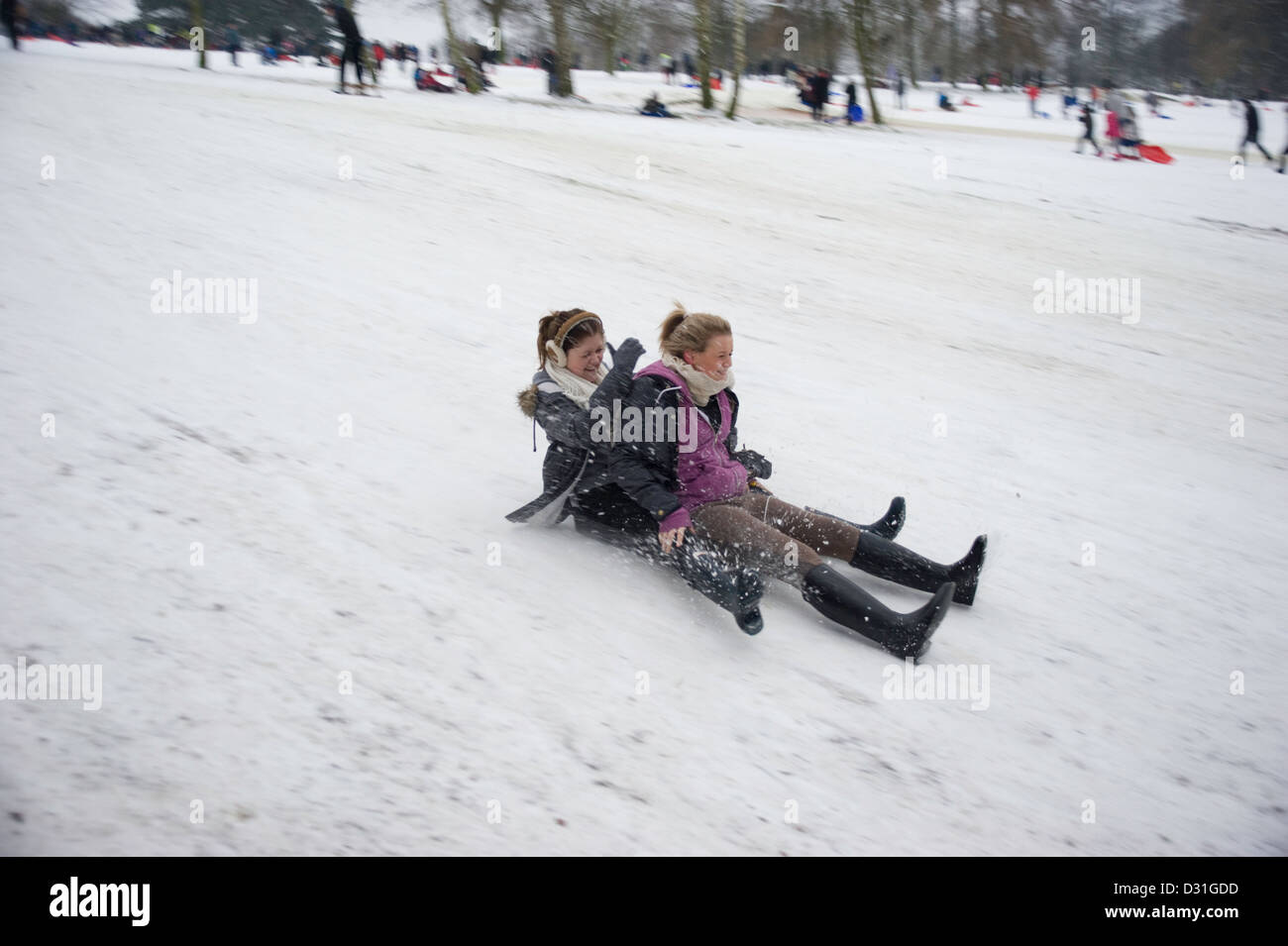 Zwei junge Mädchen im Teenageralter auf einem Schlitten oder Rodel bergab mit Geschwindigkeit im Schnee. Stockfoto