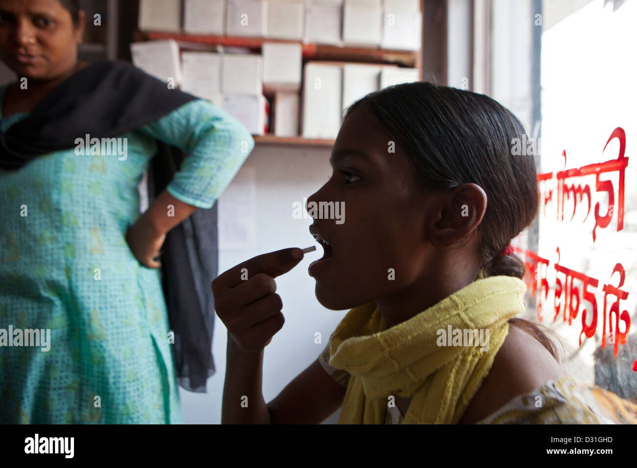 Ein Patient schluckt Tuberkulose (TB) Medikamente in einer Gesundheitsversorgung Klinik in Delhi, Indien. Stockfoto