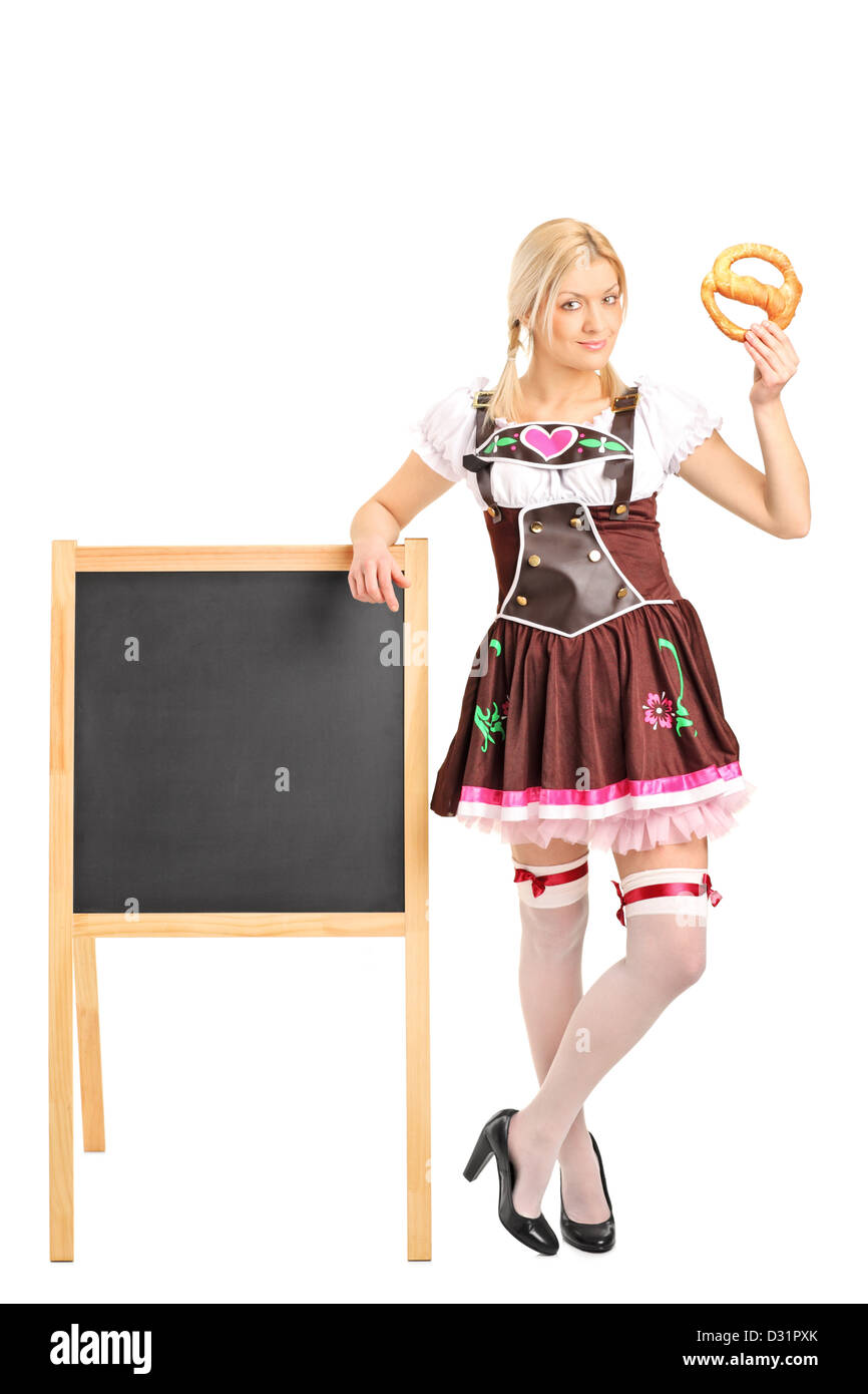 Voller Länge Porträt eines deutschen Mädchens im traditionellen Kostüm hält eine Brezel isoliert auf weißem Hintergrund Stockfoto