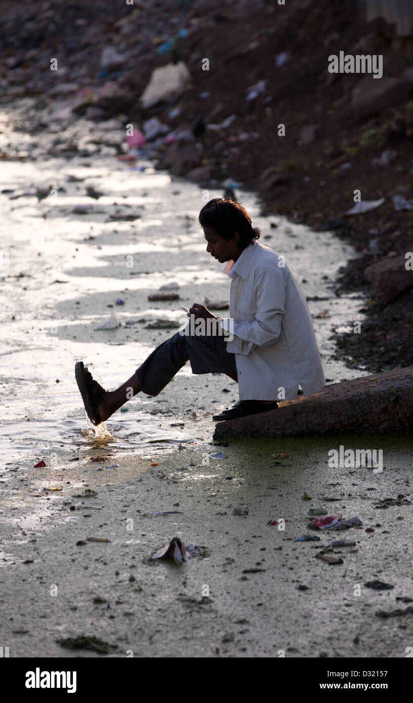 Mann seine Fußwaschung in Schmutzwasser Madhya Pradesh, Indien Stockfoto