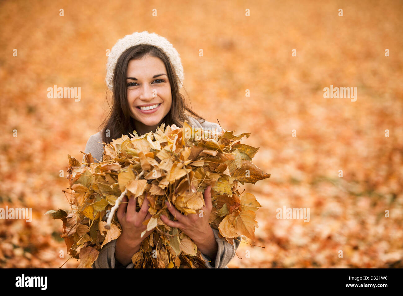 Kaukasische Frau spielt im Herbstlaub Stockfoto