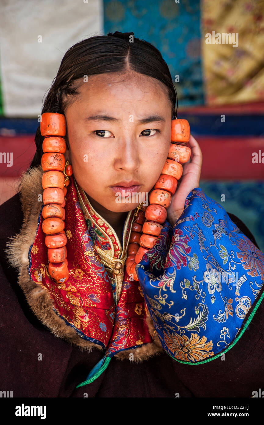 Ein tibetisches Mädchen unterstützt große korallene Perlen, die in ihr Haar, Tongren Schamane Festival gebunden sind Stockfoto
