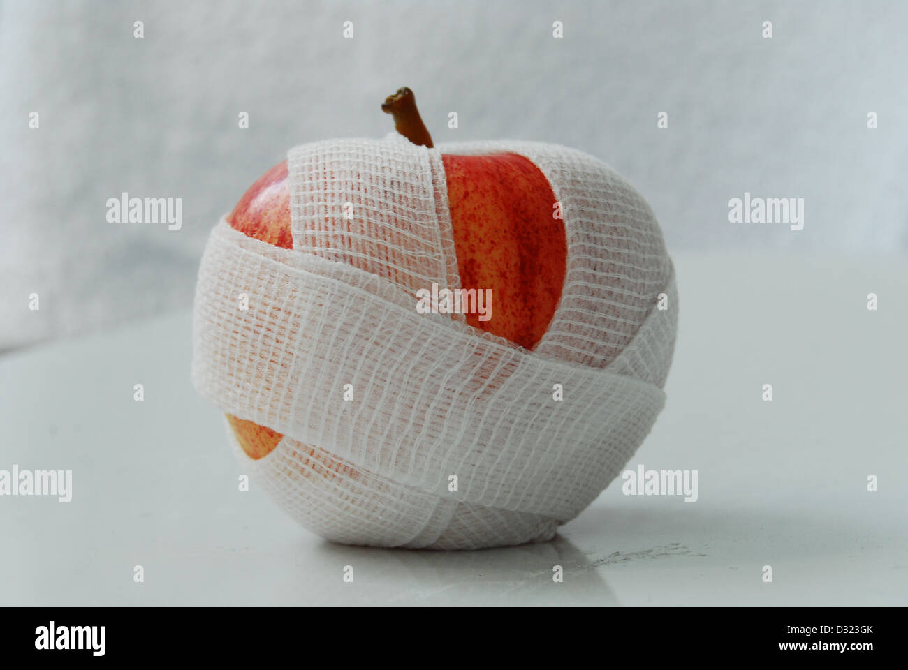 Ein roter und gelber Apfel auf einem weißen Hintergrund, eingehüllt in eine weiße Mullbinde mit einen oben genannten oder Vogelperspektive auf die Frucht. Stockfoto