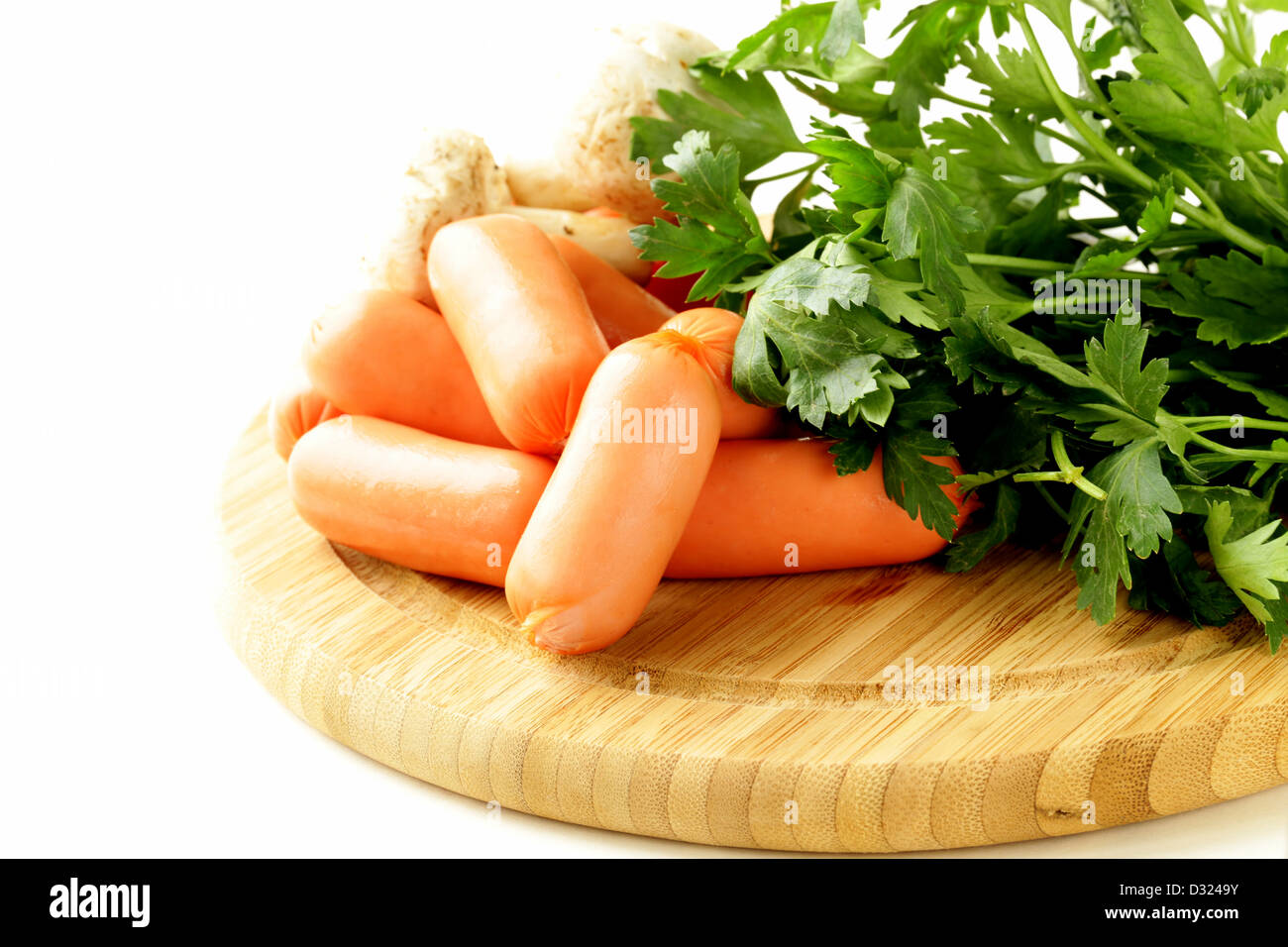 frische Würste und Petersilie auf Holzbrett Stockfoto