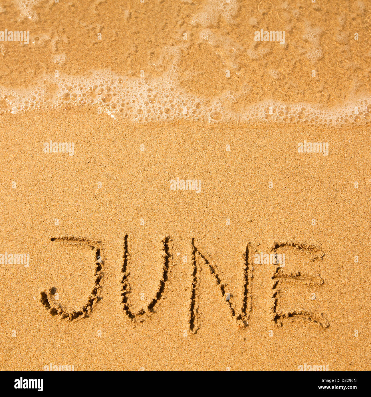 Juni - geschrieben im Sand am Strand Textur - weiche Welle des Meeres. Stockfoto