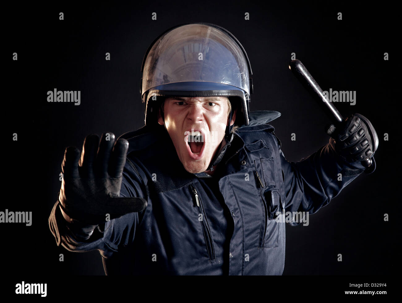 Böse Polizisten mit Gummiknüppel erzählen die gewalttätigen Menschenmenge zu stoppen Stockfoto