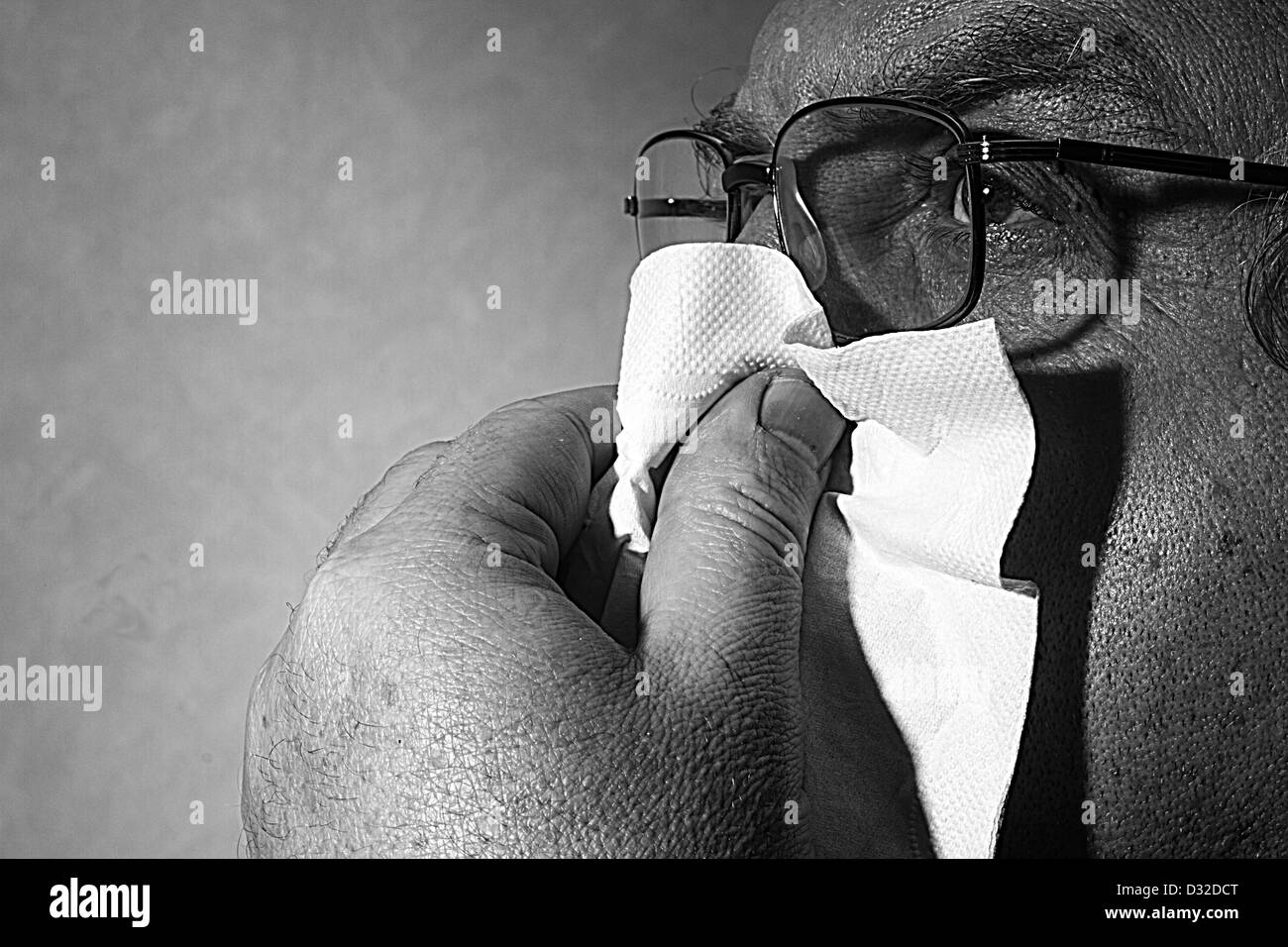im mittleren Alter Mann bläst seine Nase in ein Papiertaschentuch, schwarz / weiß Stockfoto