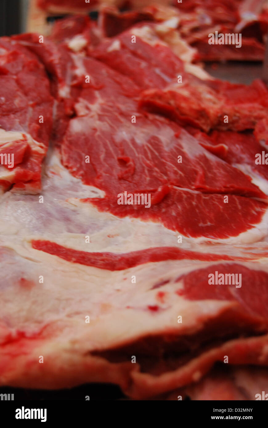 Platten von rotem und weißem Fleisch und Knochen mit Fett auf einem unordentlichen Metzger Tisch bereit, geschnitten und sortiert werden. Stockfoto