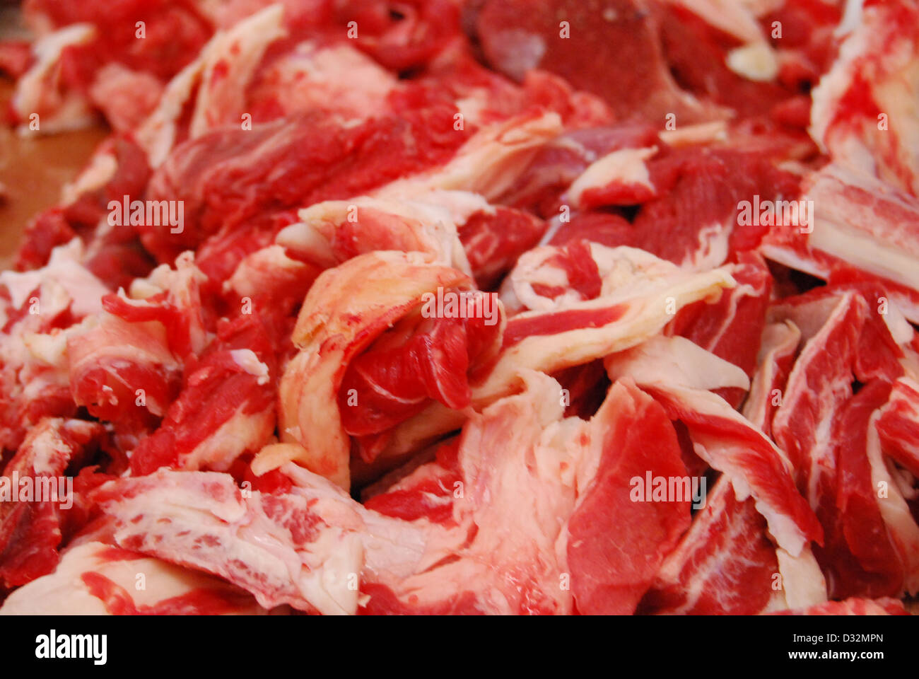 Platten von rotem und weißem Fleisch und Knochen mit Fett auf einem unordentlichen Metzger Tisch bereit, geschnitten und sortiert werden. Stockfoto